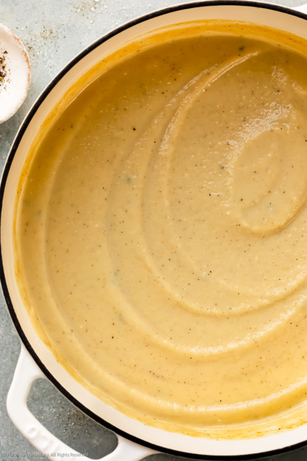 Overhead photo of creamy root vegetable soup in a large white pot.