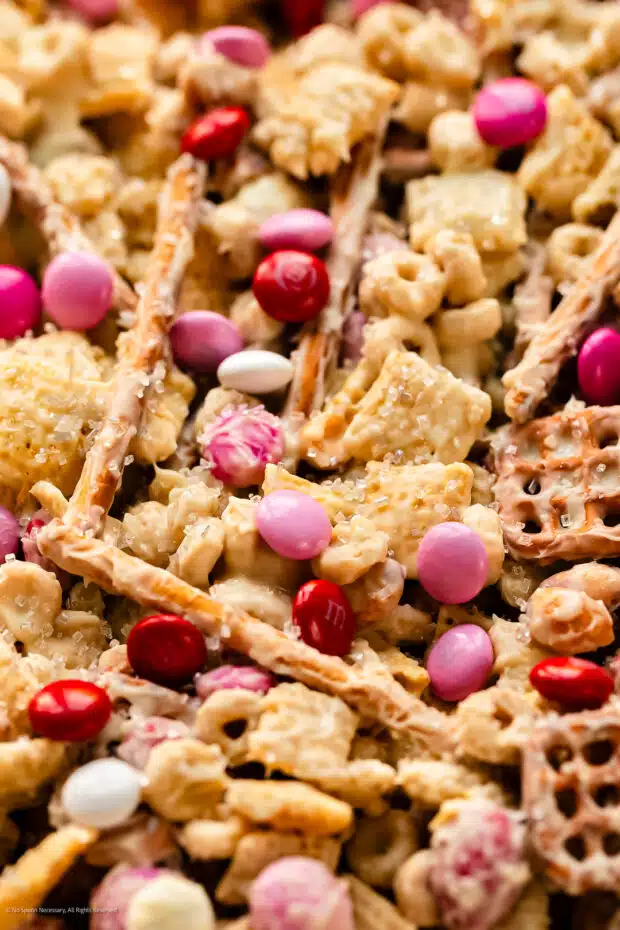 Close-up, angled photo of white trash recipe with white chocolate, chex cereal, nuts, and pretzels.