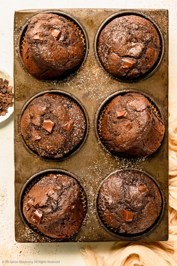 Overhead photo of freshly baked double chocolate muffins in a muffin baking pan. 