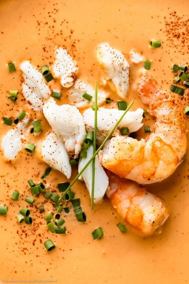 Overhead, close-up photo of Seafood bisque topped with lump crab and shrimp.