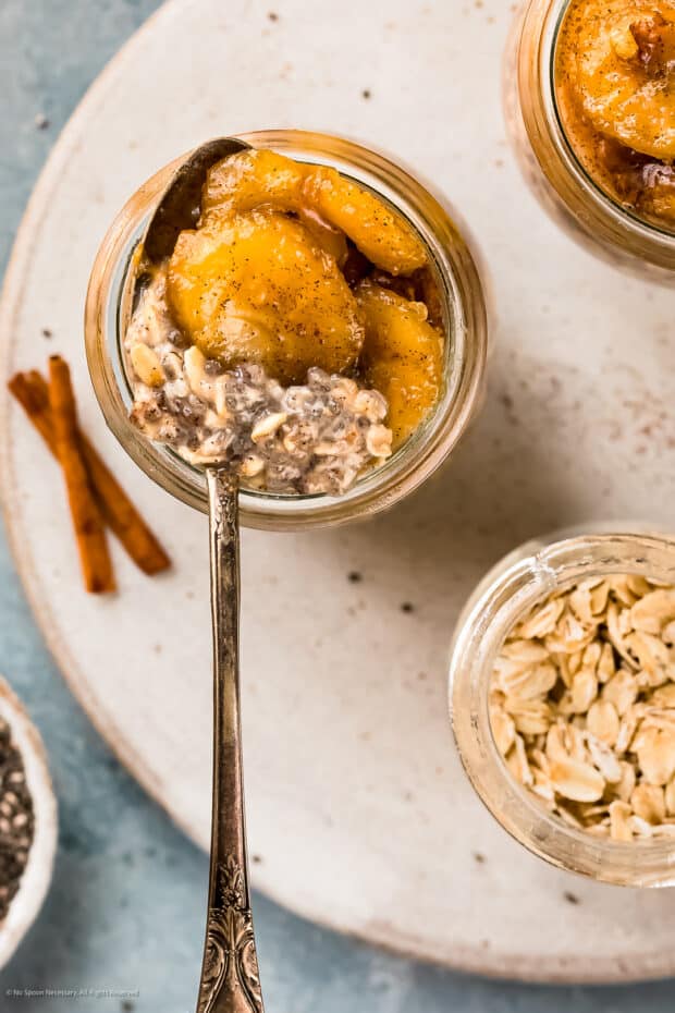 Overhead photo of overnight chia oats in a glass jar with a spoon inserted into the oats.