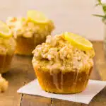 Straight on photo of a four perfect lemon muffins with crumb topping and lemon glaze.