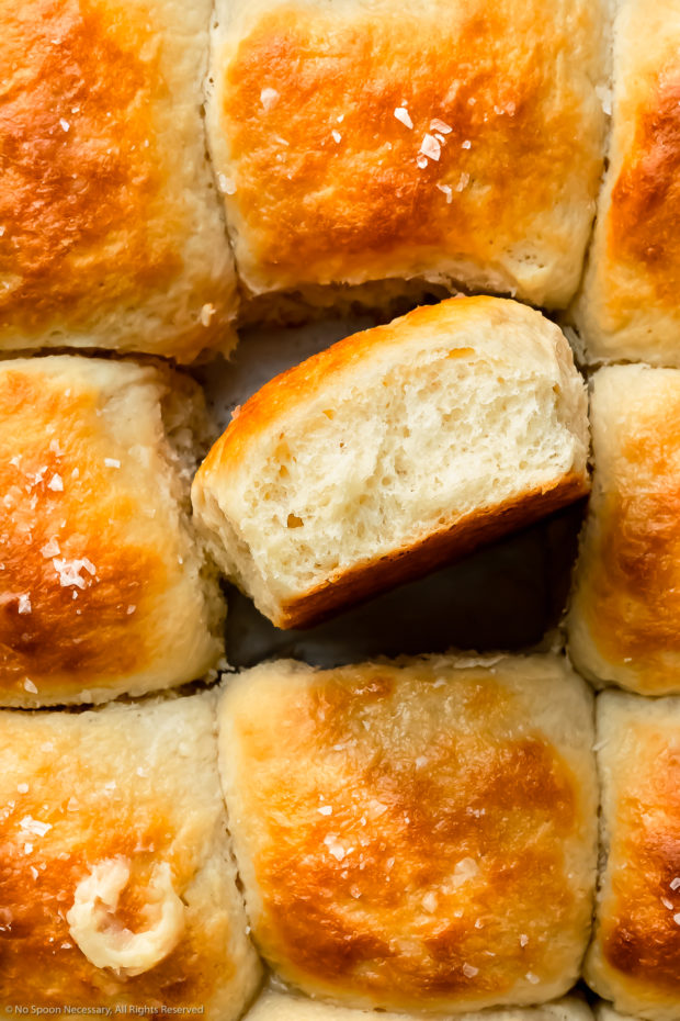 Overhead photo of pull-apart easy dinner rolls with one roll flipped on its side to showcase the soft fluffy texture.