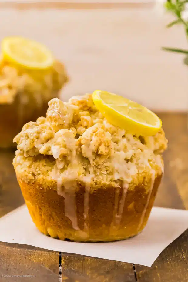 Close-up photo of a jumbo crumb muffin garnished with a slice of lemon.