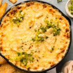 Overhead photo of crab rangoon dip topped with sliced scallions and red pepper flakes in a cast iron skillet.