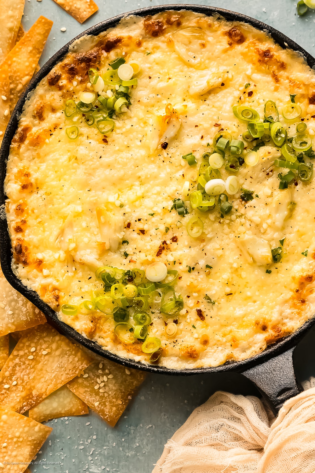 Overhead photo of crab wonton dip in a large skillet with baked wonton chips surrounding the skillet.