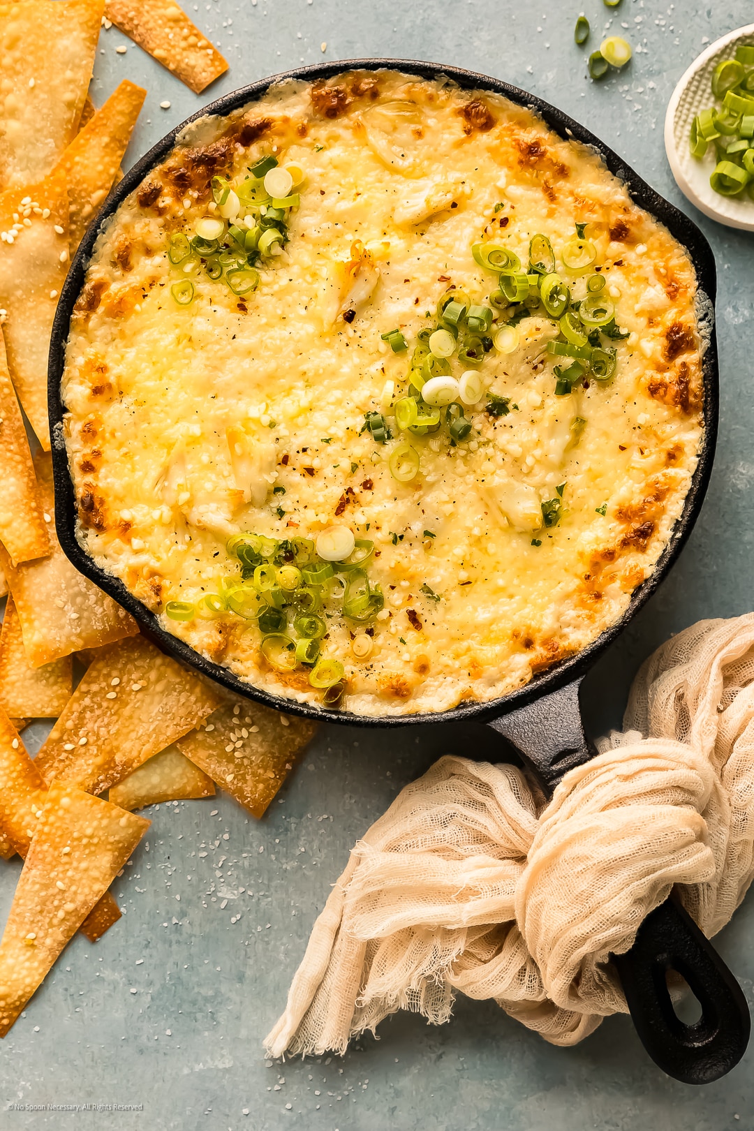 Overhead photo of baked crab rangoon dip in a large black skillet.