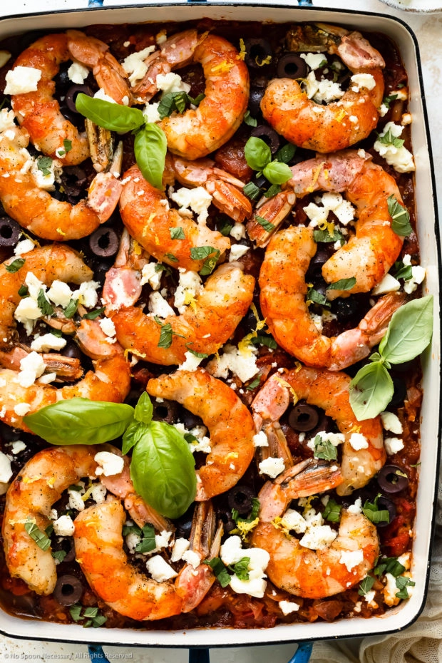 Overhead photo of baked shrimp saganaki with tomatoes and feta in a 9x13-inch baking dish.