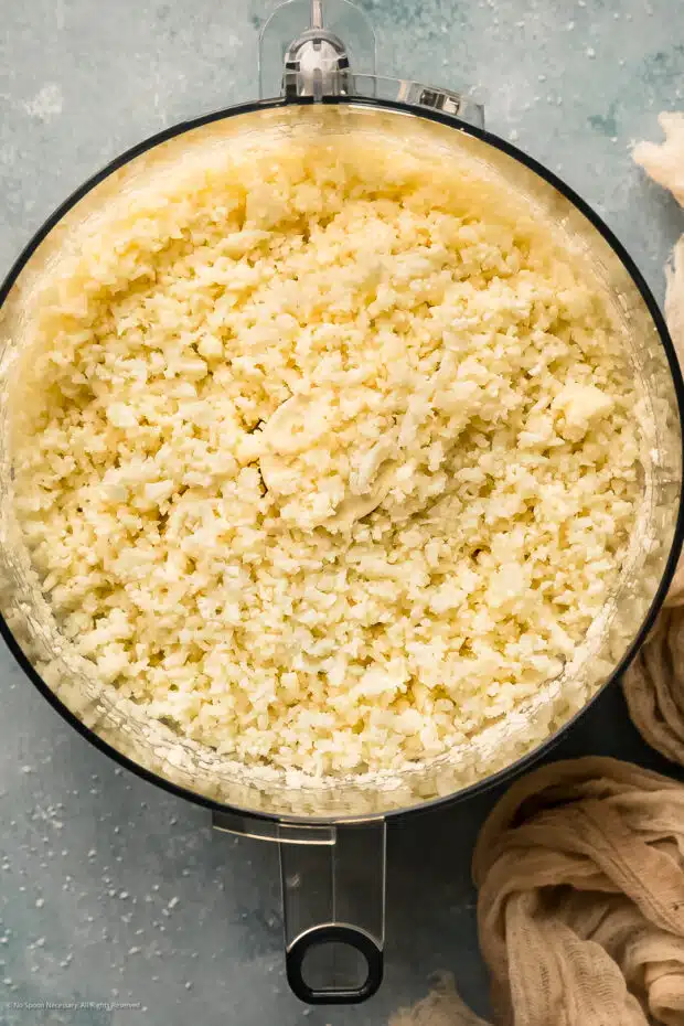 Photo of riced cauliflower in a food processor bowl.