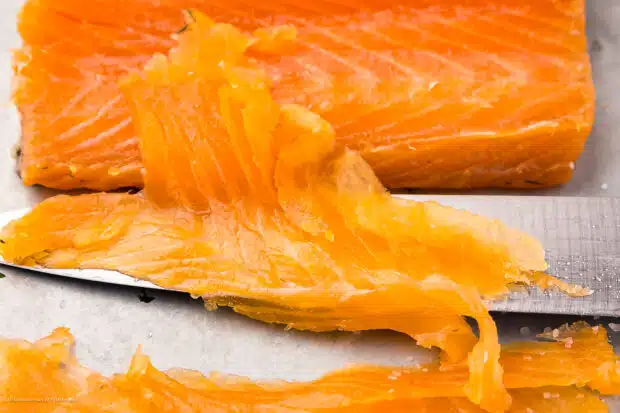 Straight on photo of a gravlax of salmon sliced thin.