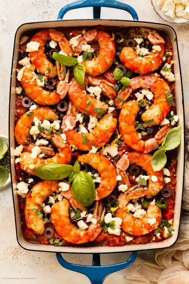 Overhead photo of baked Greek shrimp saganaki with tomatoes and feta in a baking dish.