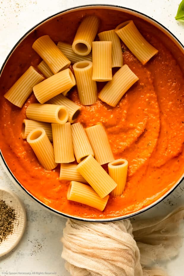 Overhead photo of pasta noodles in a pot of pepper sauce.