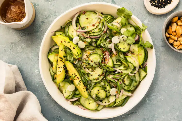 Overhead photo of Asian cucumber salad with red onions in a white bowl.