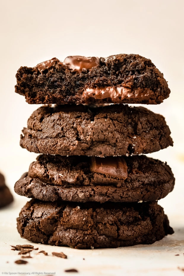 Straight on photo of a stack of triple chocolate cookies, with the focus on the top cookies fudgy center.