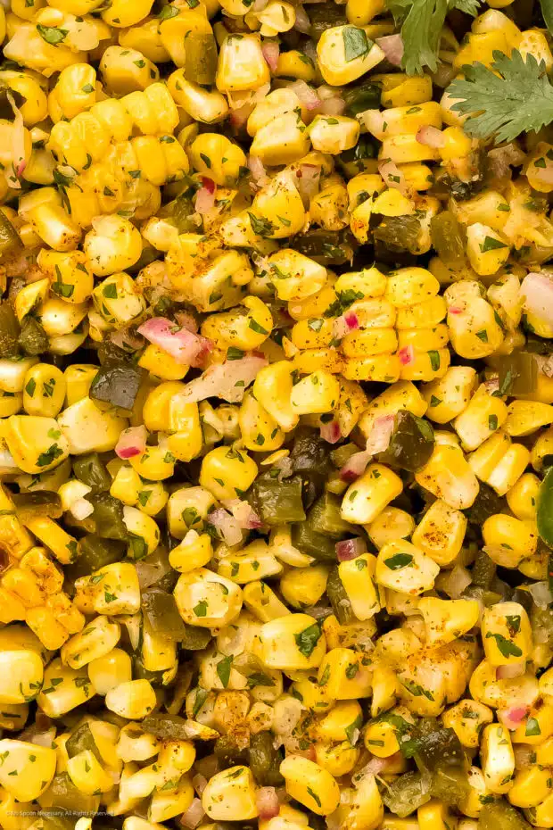 Overhead, extreme close-up photo of homemade roasted corn salsa recipe with peppers and onions.