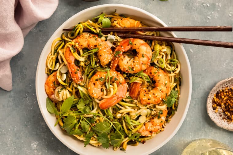 Overhead photo of garlicky shrimp and zucchini pasta in a white bowl.