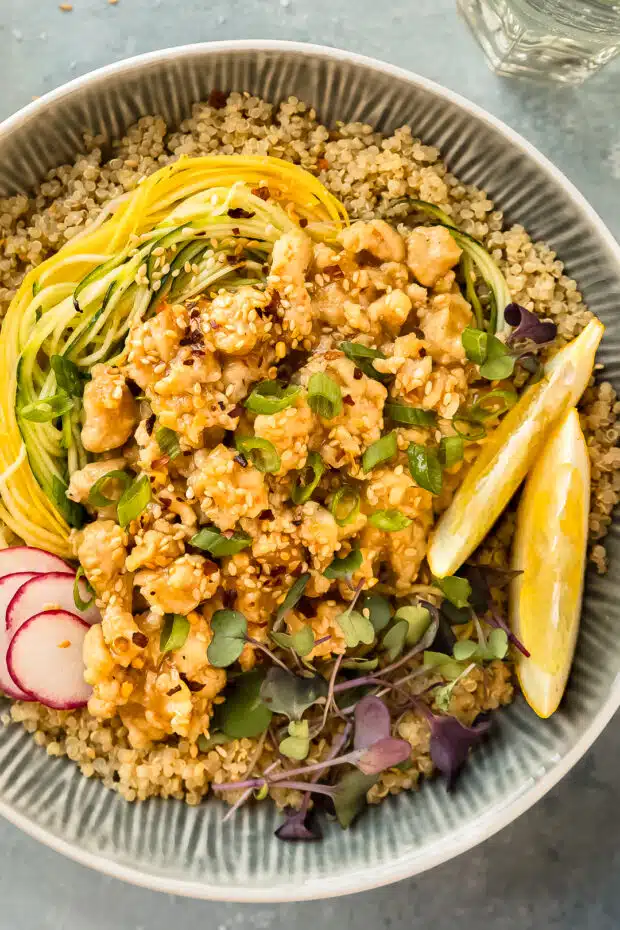 Overhead photo of a bowl of ground chicken stir fry with fresh vegetables, quinoa, and lemon sauce.