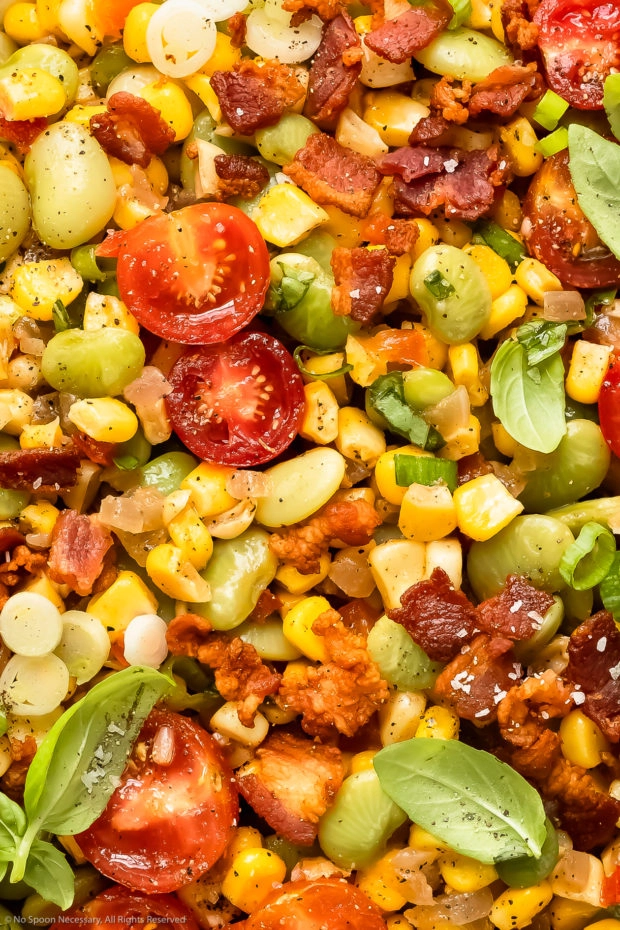 Overhead, close-up photo of succotash with corn, lima beans, tomatoes, bacon and fresh herbs. 