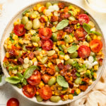 Overhead photo of sweet corn succotash with bacon and tomatoes in a white serving bowl.