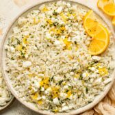 Overhead photo of lemon rice with lemon zest, dill, and feta in a white bowl.