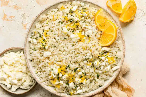 Overhead photo of lemon rice with lemon zest, dill, and feta in a white bowl.