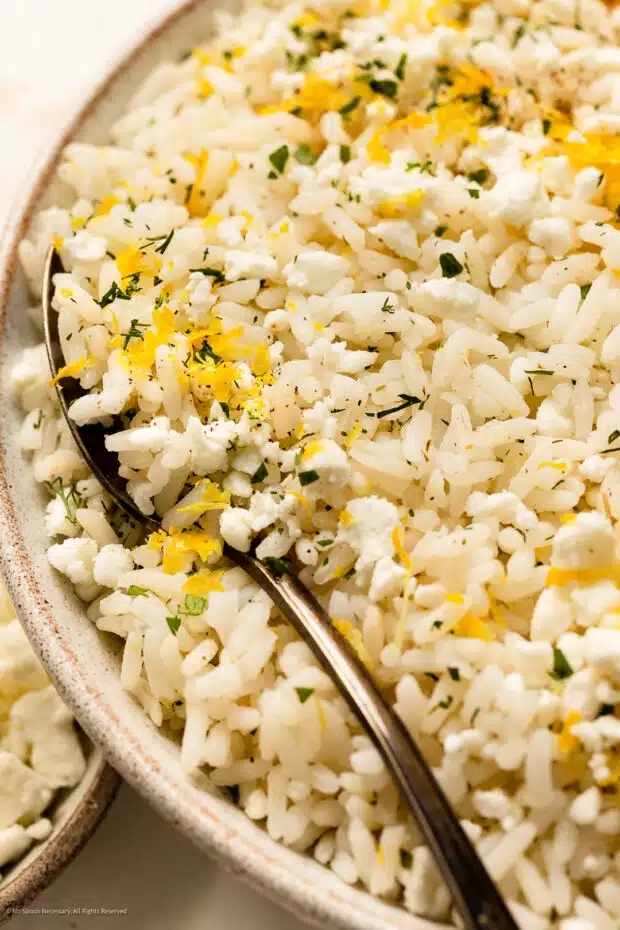 Close-up photo of cooked recipe for lemon rice with lemon zest and fresh herbs.