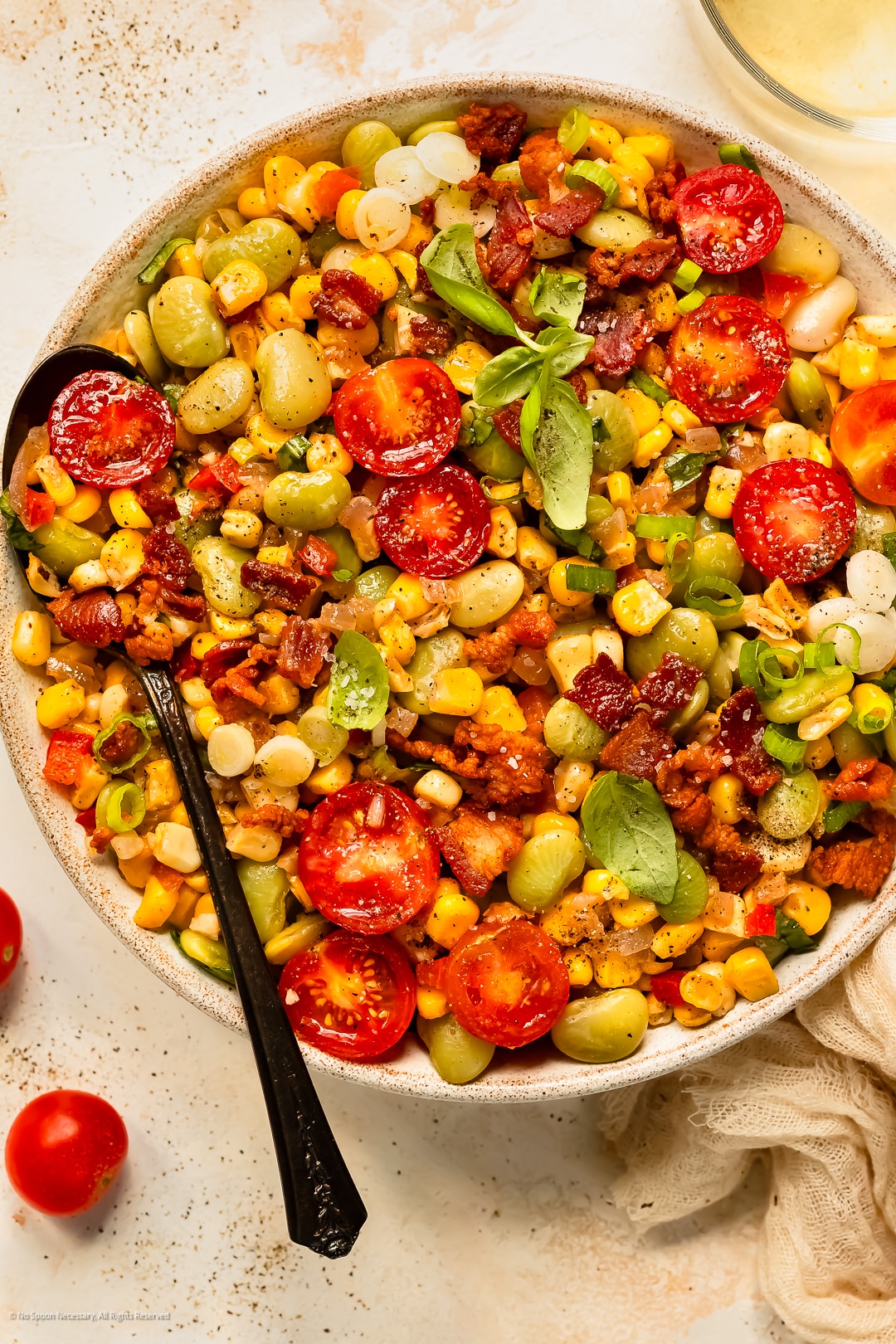 Overhead photo of succotash corn and lima beans in a serving bowl with a spoon inserted into the dish.