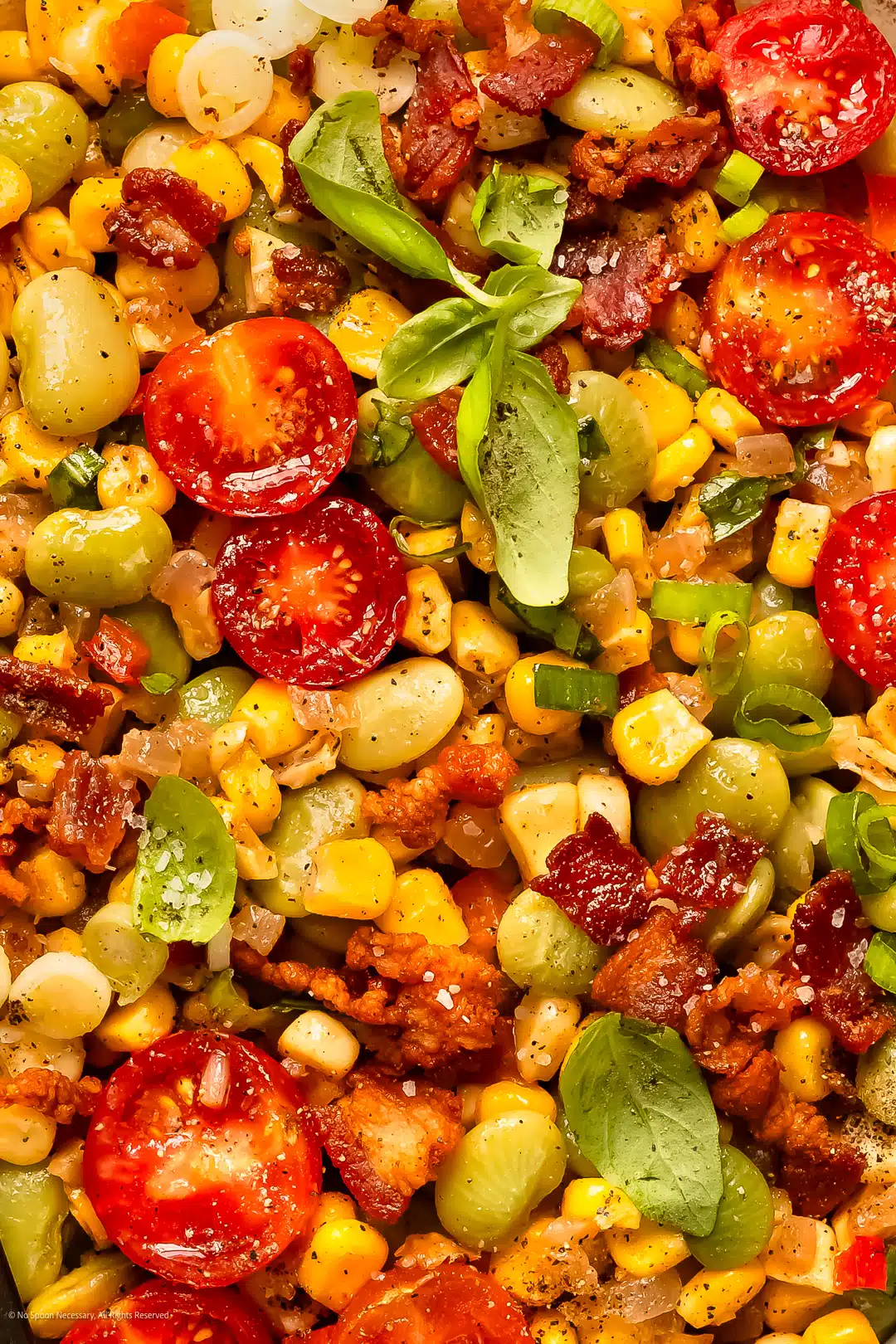 Close-up photo of sweet corn succotash with lima beans, bacon, corn, and fresh herbs.