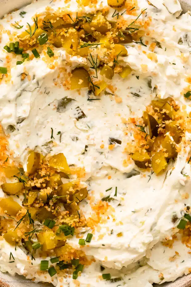 Close-up photo of the creamy texture and pickle topping on bowl of fried pickles ranch dip.