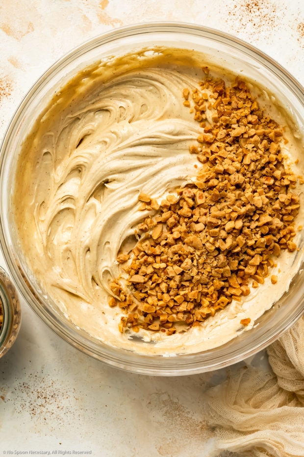 Overhead photo of whipped no-bake cheesecake dip topped with toffee bits in a large glass mixing bowl.