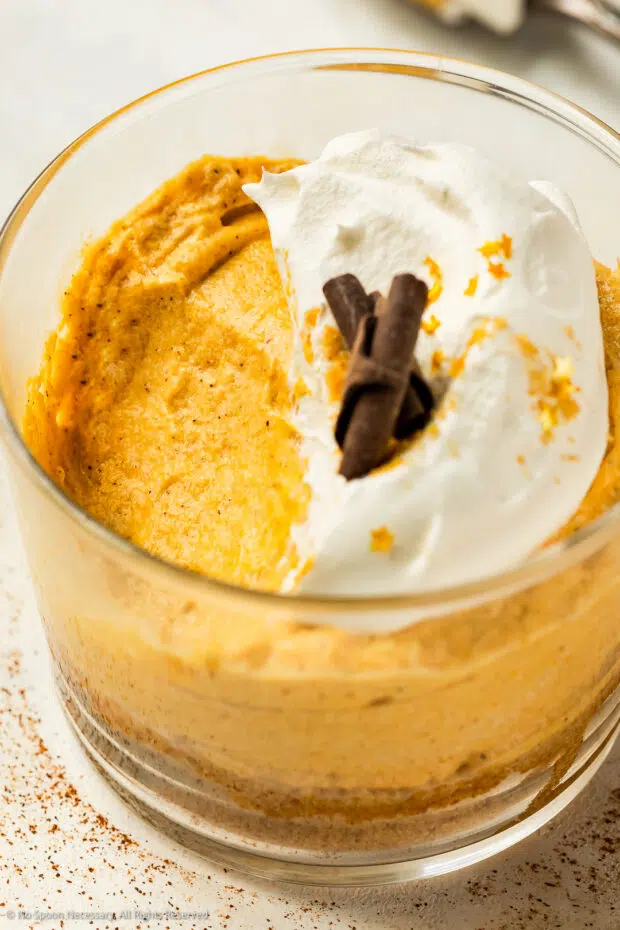 Angled, close-up photo of pumpkin mousse with a bite missing in a short dessert glass.