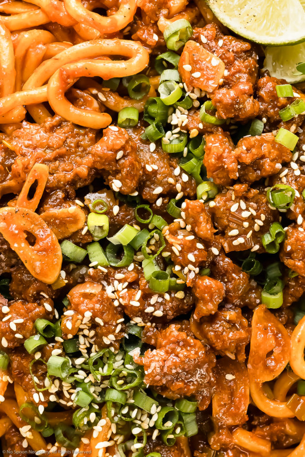 Overhead, close-up photo of Pork Yaki Udon Noodles garnished with sesame seeds and sliced scallions.