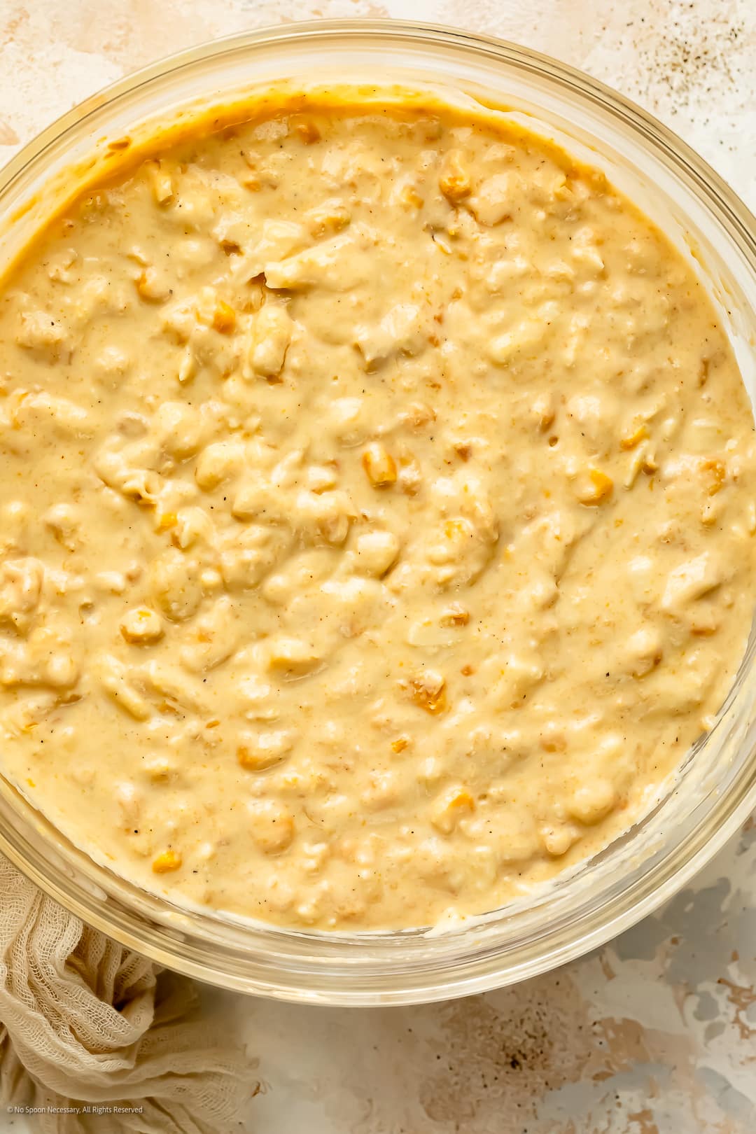 Overhead photo of raw corn casserole without jiffy mix batter in a large mixing bowl.