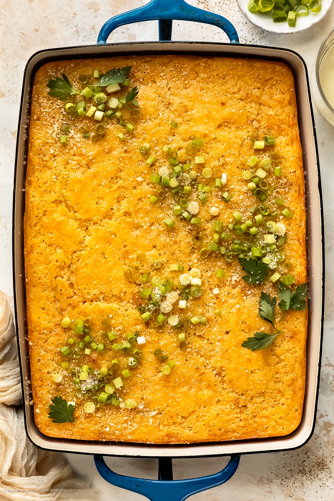 Overhead photo of freshly baked corn pudding casserole without jiffy mix in a blue casserole dish.