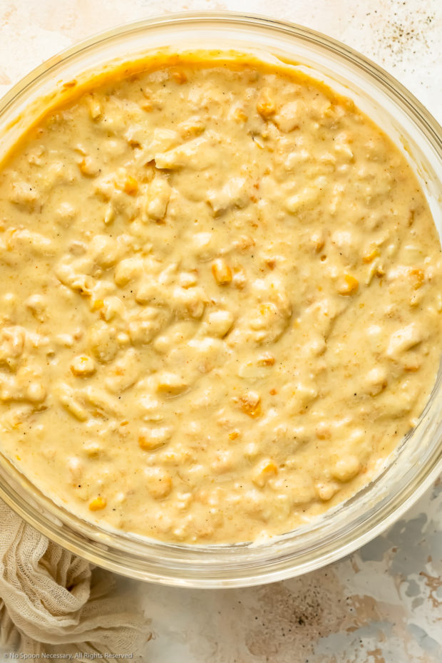 Overhead photo of a glass mixing bowl filled with creamed corn casserole batter.