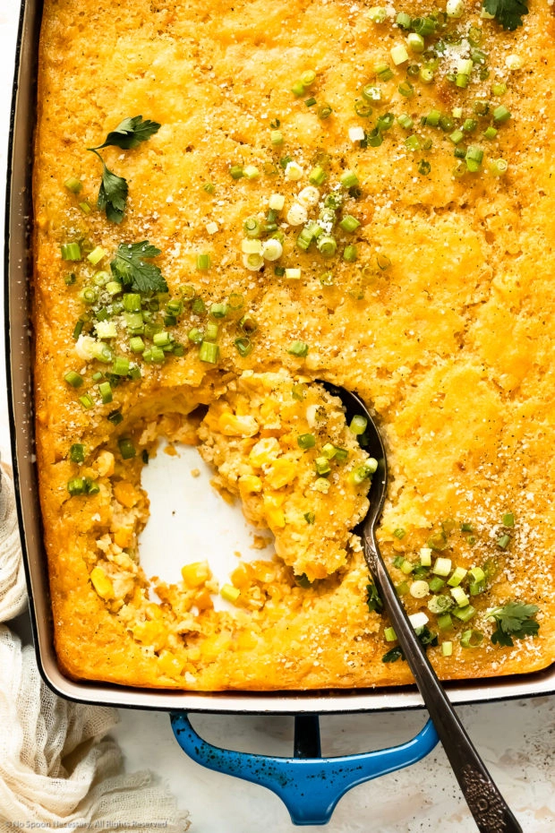 Overhead photo of cream corn casserole with a spoon scooping up the casserole to showcase the interior.
