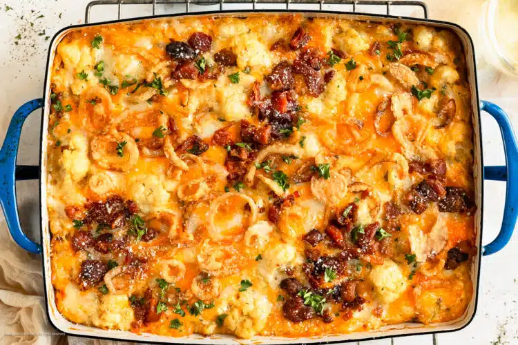 Overhead photo of a loaded cauliflower casserole in a baking dish cooling on a wire rack.