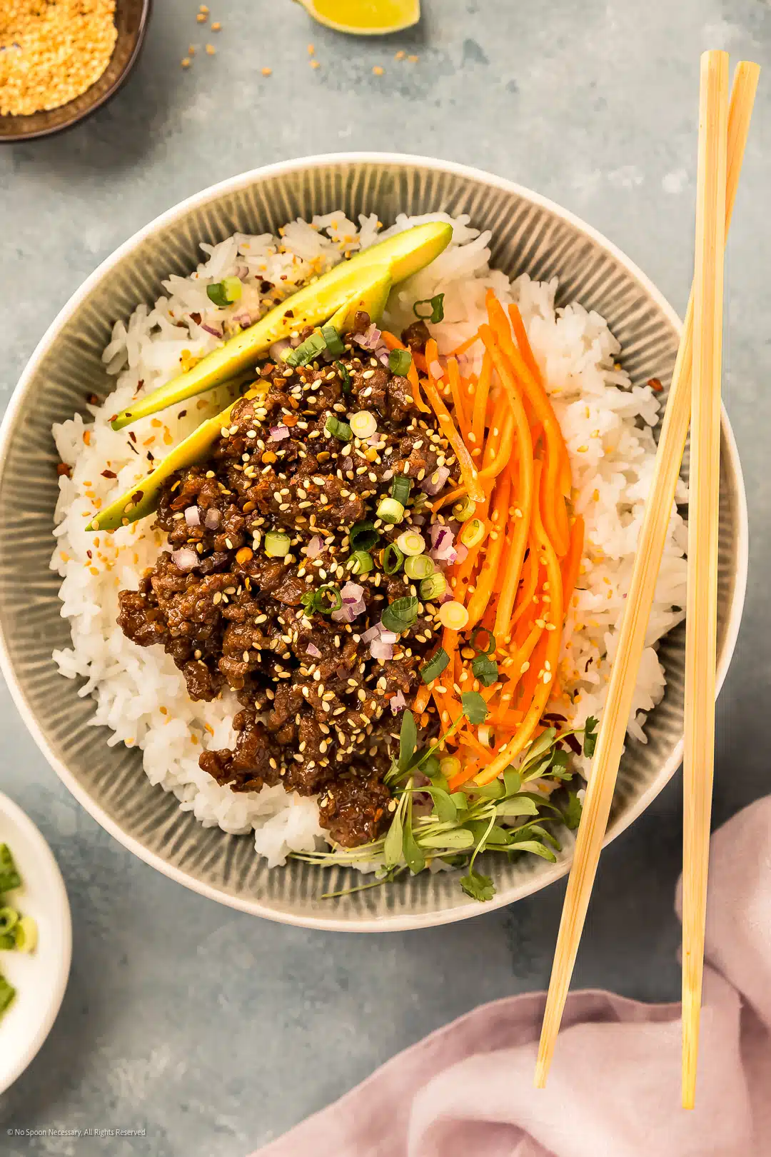 Overhead photo of chinese ground beef with mushrooms, hoisin sauce, and sesame seeds in a serving bowl over white rice.