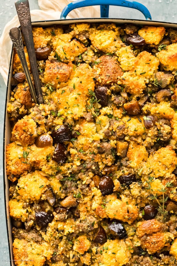 Close-up photo of stuffing with chestnuts, sausage, and cornbread in a blue casserole dish.