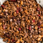Overhead, landscape photo of dark chocolate granola in a parchment paper lined pan.