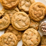 Overhead photo of a dozen cinnamon cookies and a jar of cinnamon chips on a white platter.