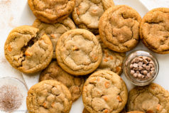 Overhead photo of a dozen cinnamon cookies and a jar of cinnamon chips on a white platter.