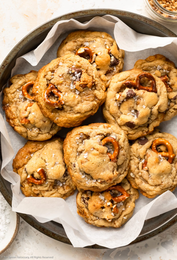 Overhead photo of nine kitchen sink cookies piled into a parchment paper-lined antique pan.