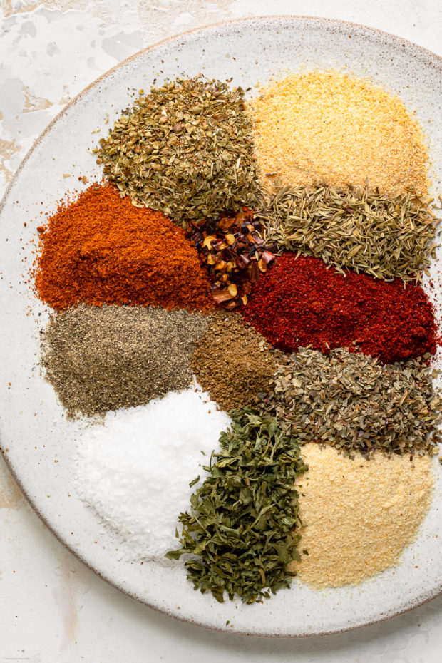 Overhead photo of all the spices and dried herbs in Cajun seasoning neatly arranged on a plate.