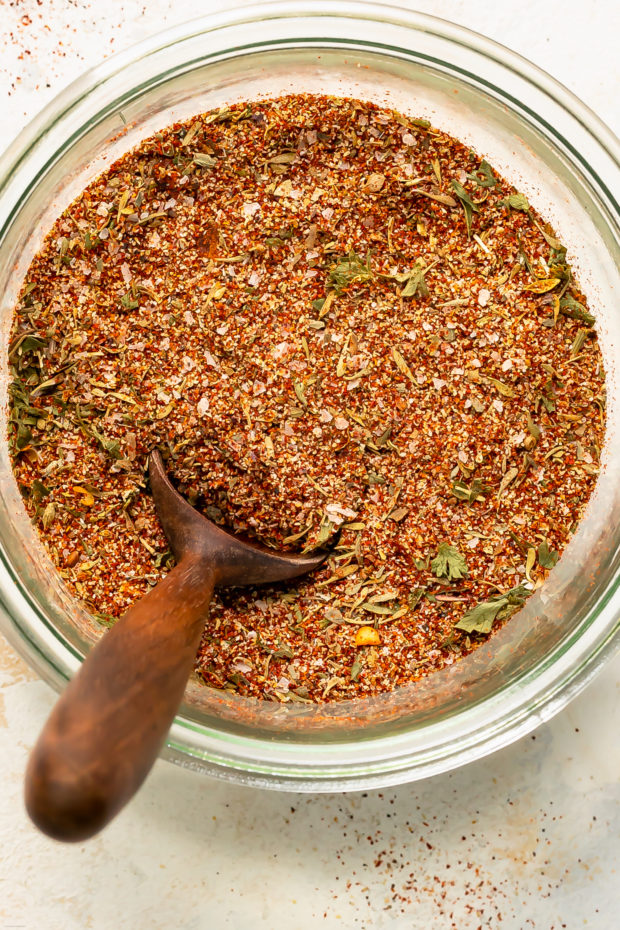 Overhead photo of Cajun spice mix in a glass jar with a small wooden spoon inserted into the jar.