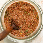Overhead photo of a jar of Cajun spice with a small spoon inserted into the jar.