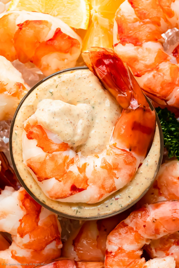 Overhead photo of a cocktail shrimp laying on top of a small bowl of homemade remoulade. 