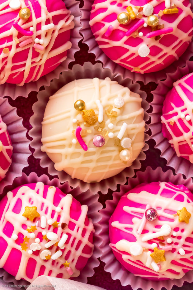 Overhead photo of a white cake pop surrounded by vibrant pink cake pops