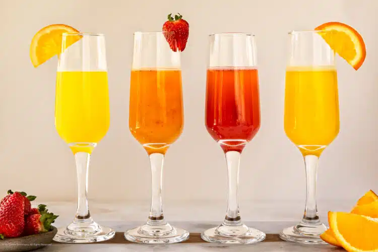 Straight on photo of four different mimosa drinks.