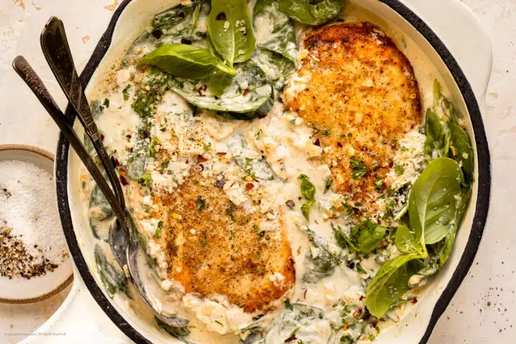Overhead photo of florentine chicken with creamy spinach in a white skillet.